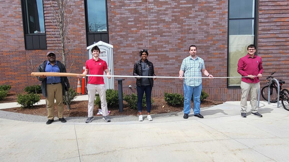 Five people hold giant conductor's baton