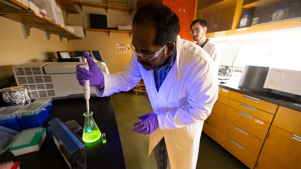 Man putting glowing material into a vial