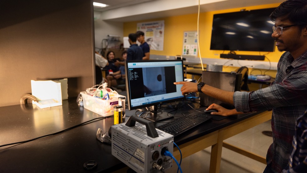 Students launch balls through PVC tube and capture images with high speed camera
