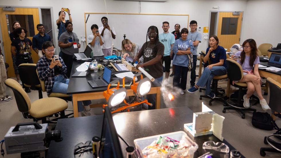 Students launch balls through PVC tube and capture images with high speed camera