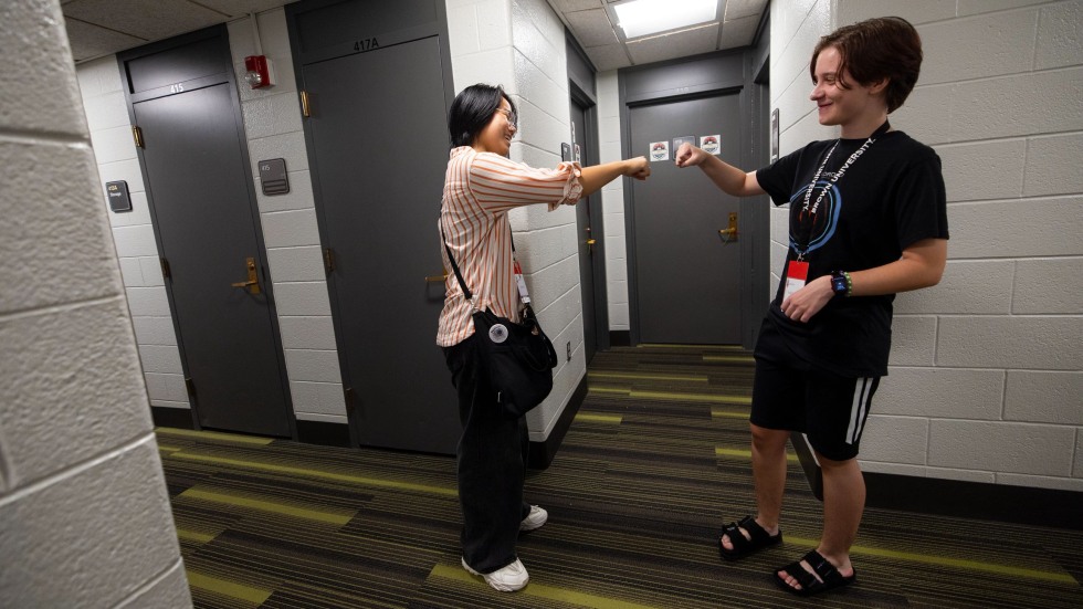 Irene Chen and Violet Dellinger fist-bump in the residence hall