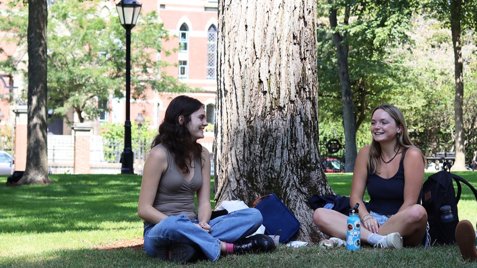 Zoe Rudolph-Larrea and Kaitlyn Lucas sit on the grass