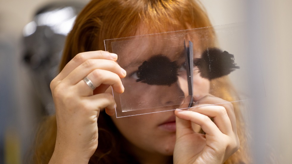 Zoe Goldemberg holds a piece of film up to her eyes 