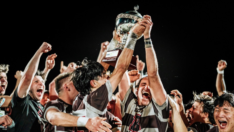 Rugby team holds up trophy and cheer after winning title 