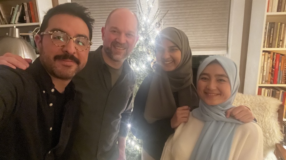 four people pose for selfie, backlit by Christmas tree