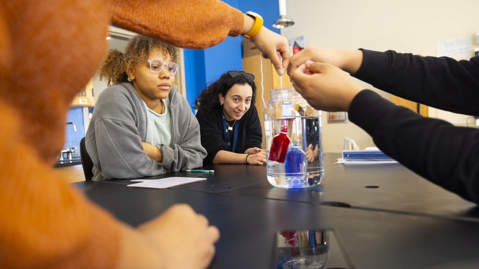 students drop bottles of warm (red) and cold (blue) water held within jars of room-temperature water