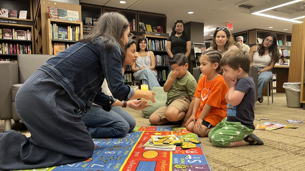 kids gather on a colorful rug on the floor to make a wish with a candle