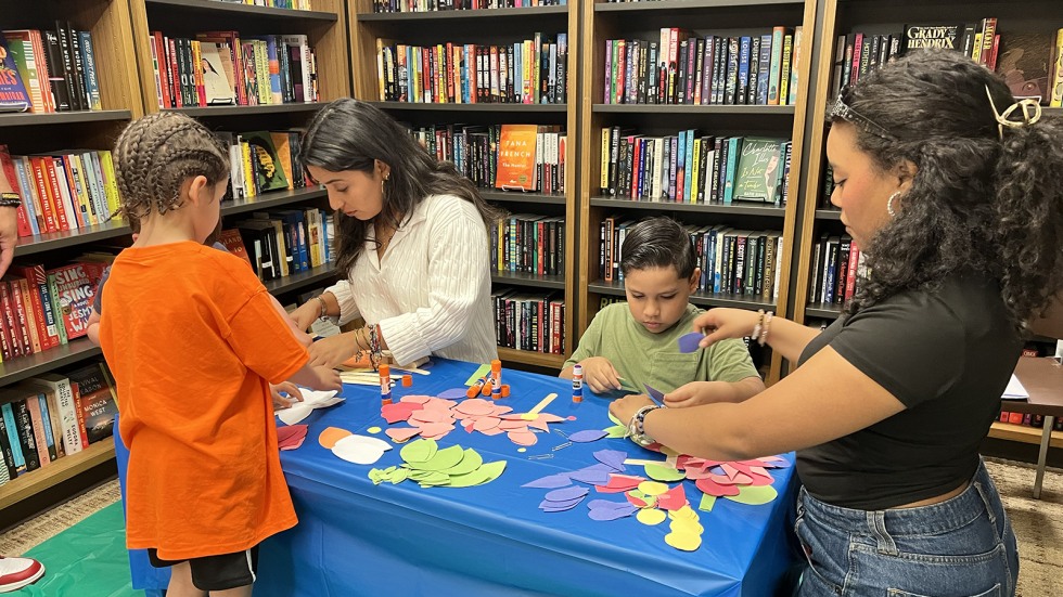 Brown students work with kids to create paper flowers