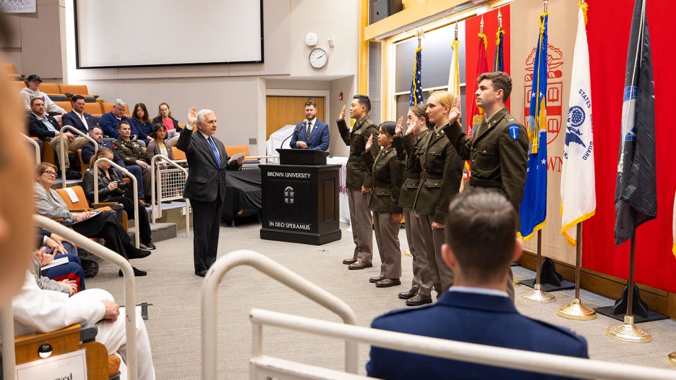 New officers stand with their right hands raised as Sen. Jack Reed reads their oath