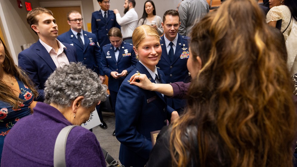 A newly commissioned officer is surrounded by family and friends offering congratulations