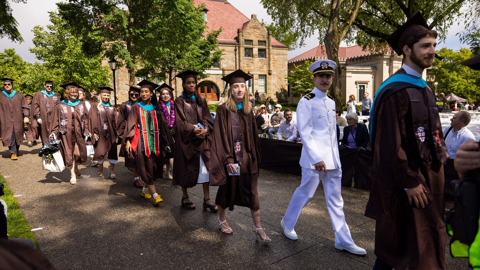 An image of students, one in a military uniform, walking to their seats on the College Green