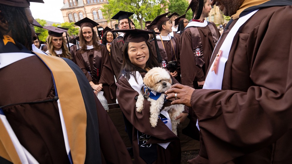 A photo of a graduate holding a small dog