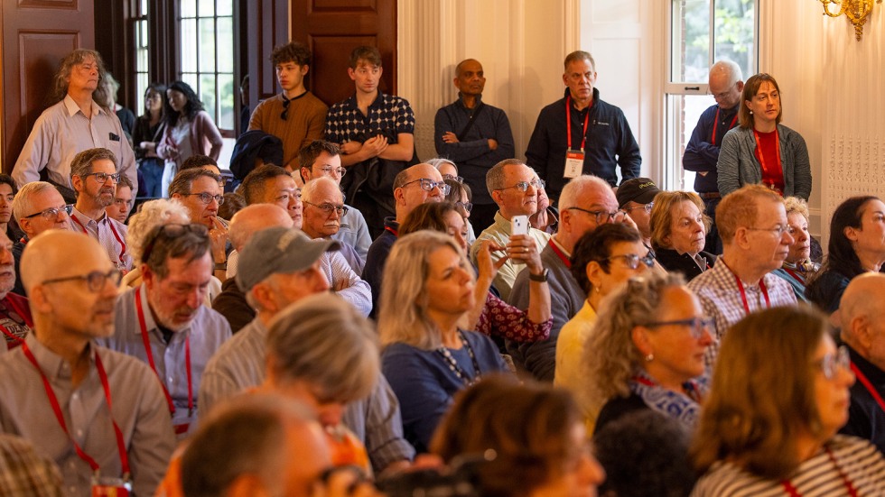 people gather in a room listening to a speaker