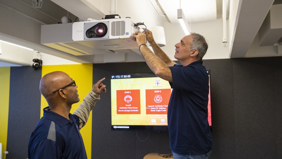 Workers from a local company install audio-visual technology in a classroom. 