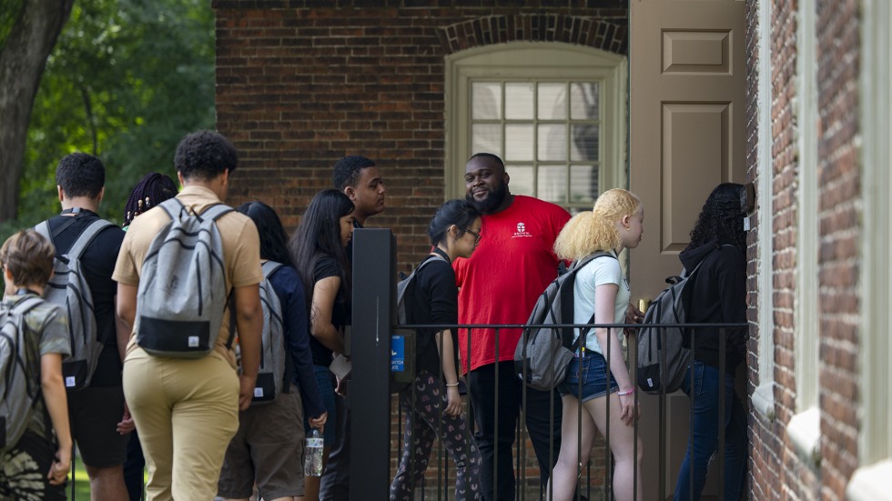 Brown staff member holds a door for students as they tour through buildings on campus. 