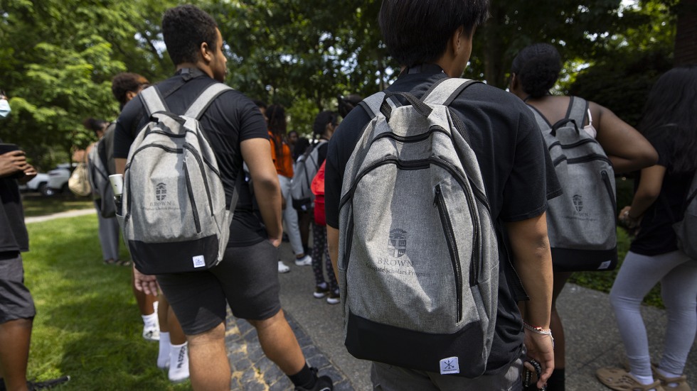 Students walk through campus with their Brown backpacks.