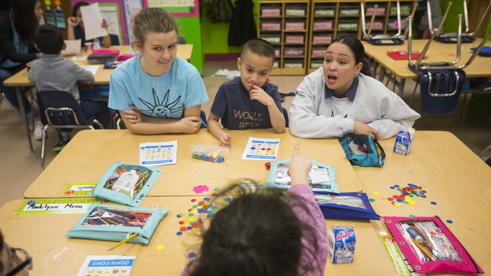 Inoa sits at table, leading kids through learning games