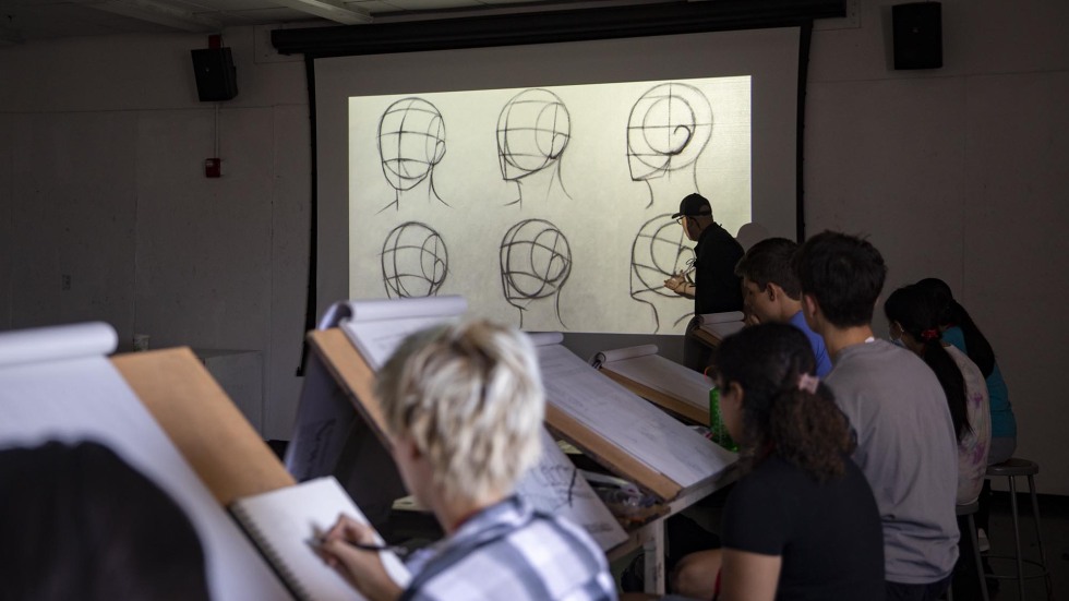 students draw human head figure on large easels as part of drawing course