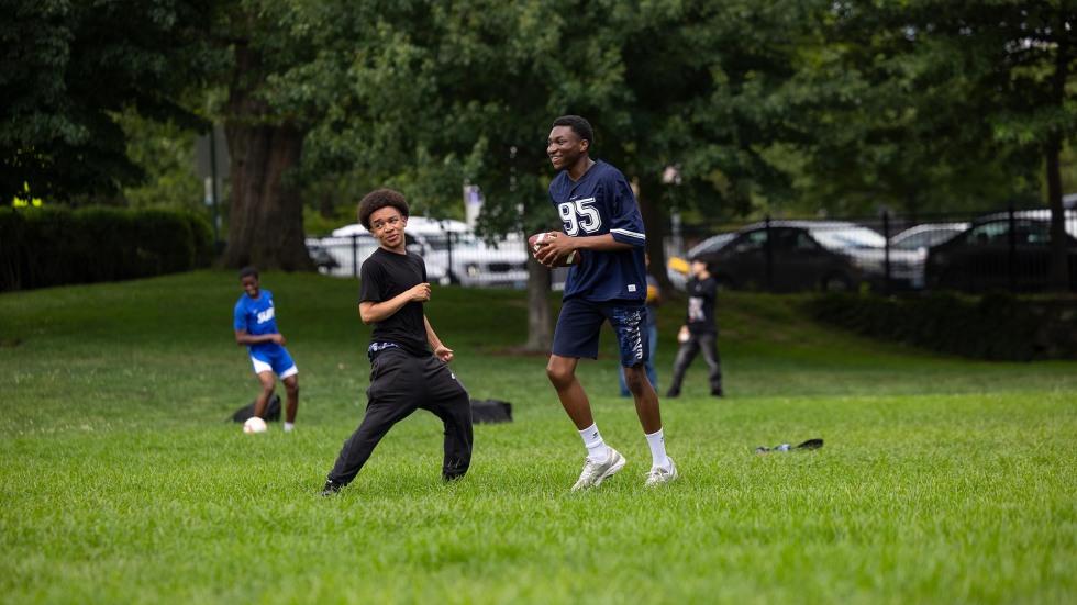 students enjoy a game of football on a grassy field