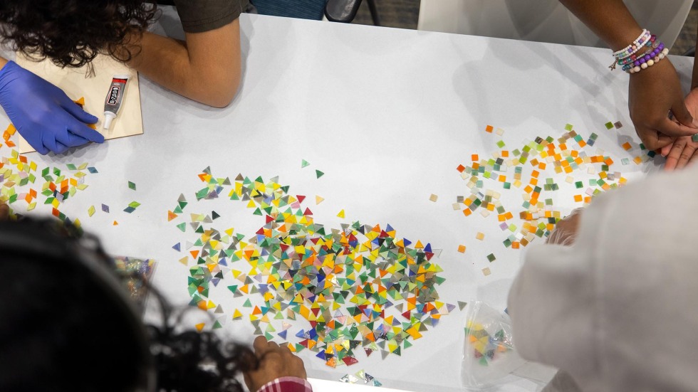 up close shot of students hands' working with small shapes to form mosaics.