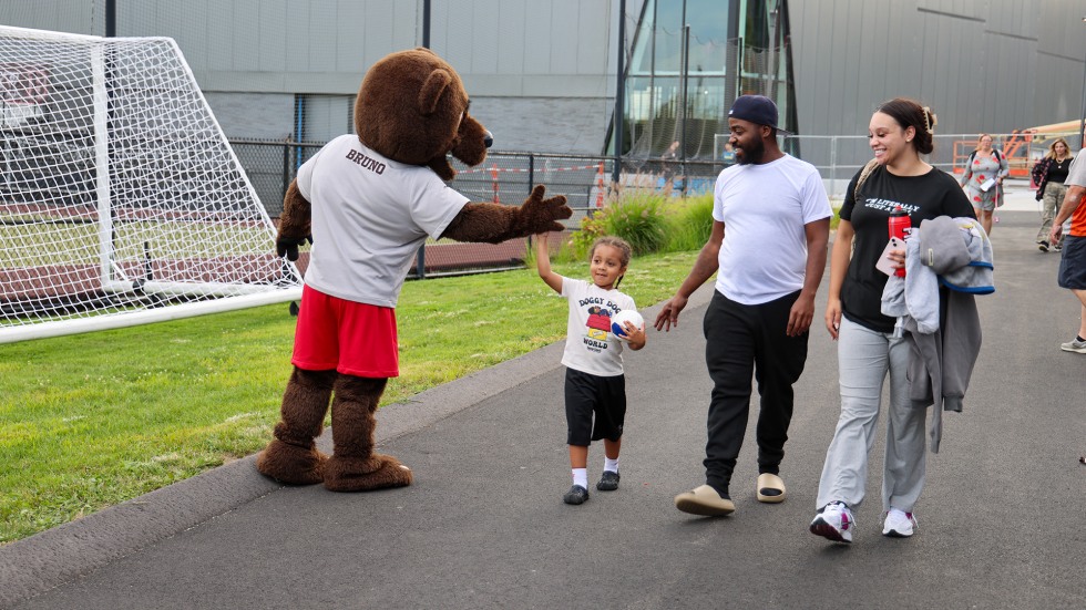 Bruno the bear stops a family walking into the campus for a high-five.