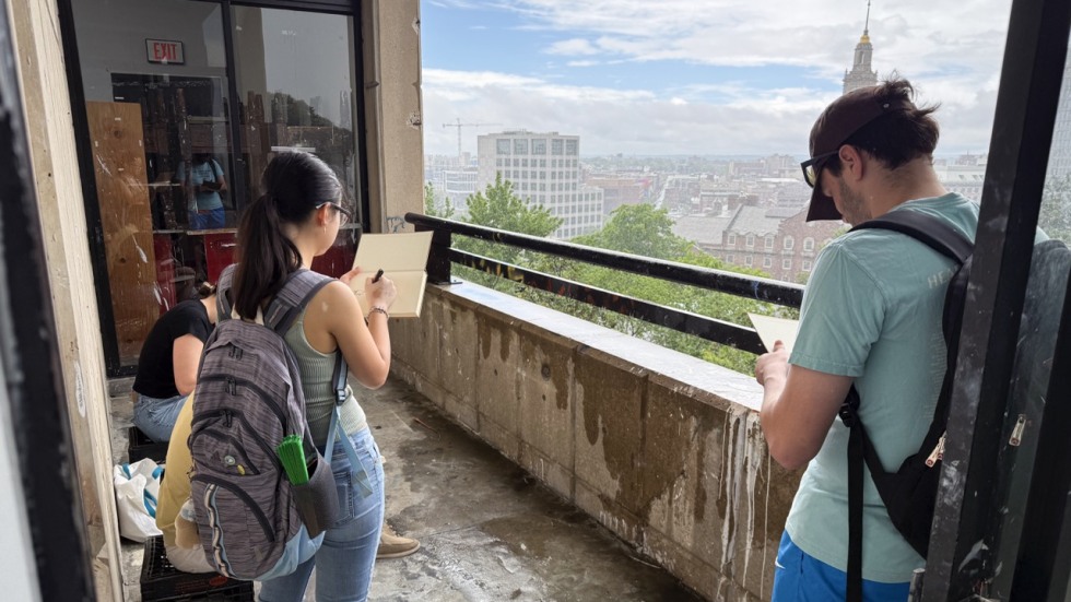 Students work on sketches on a balcony