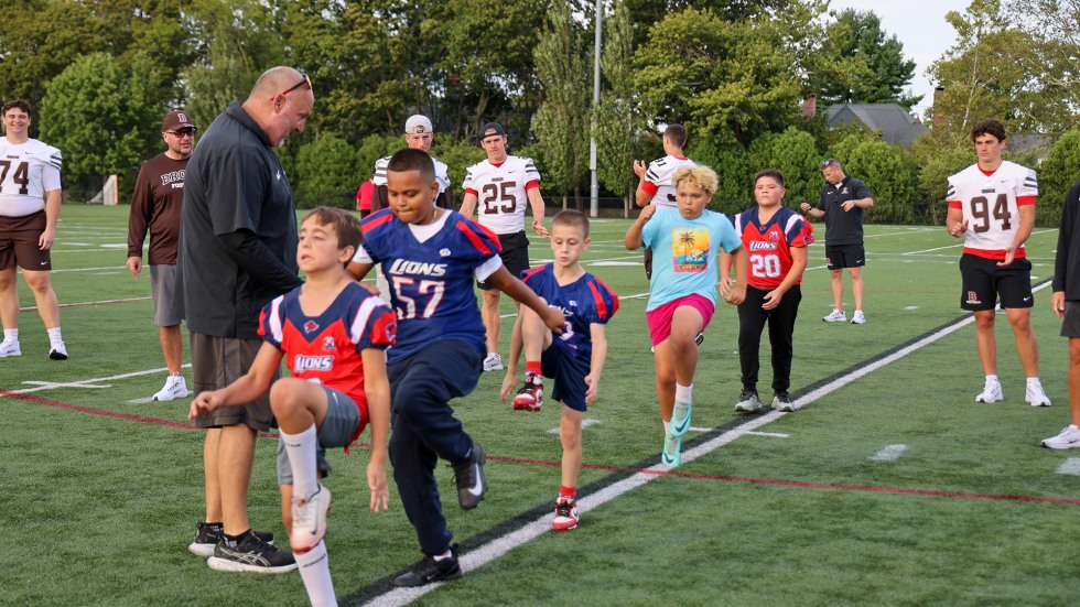 Local kids practice high knee jumps on field. 