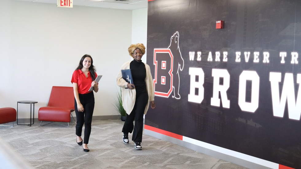 Two local high schoolers walk through Brown Athletics office to a meeting.