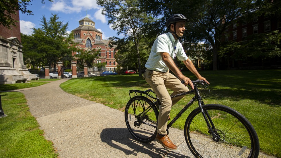 John Colarusso rides on his bike across Brown's campus