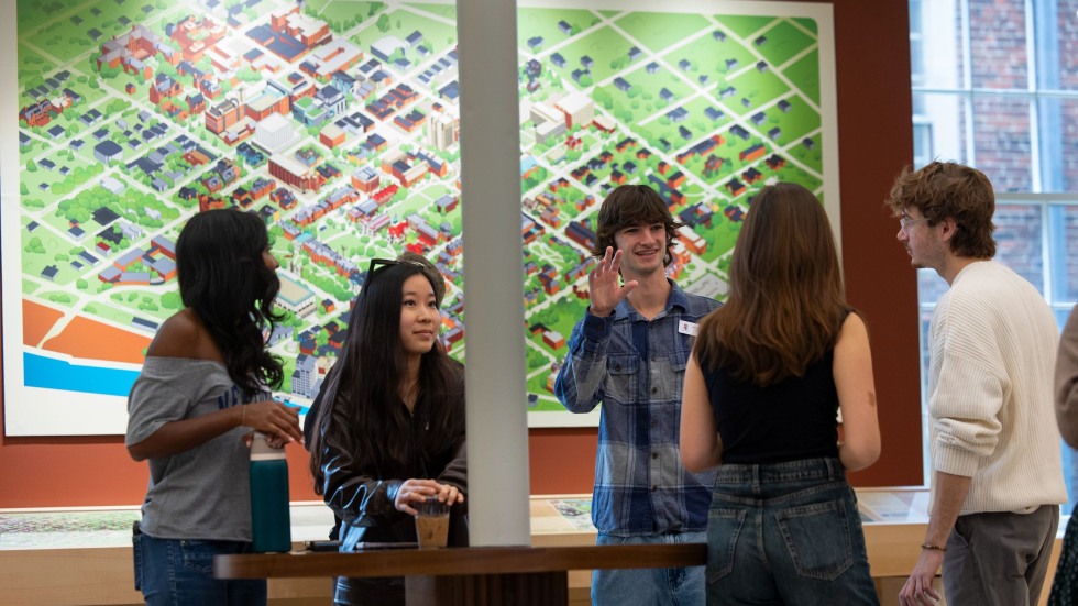 five people talk in front of 2D wall map