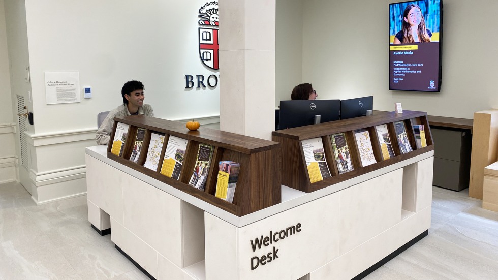 Nakhil Ahn sits at the welcome desk in the admission welcome center