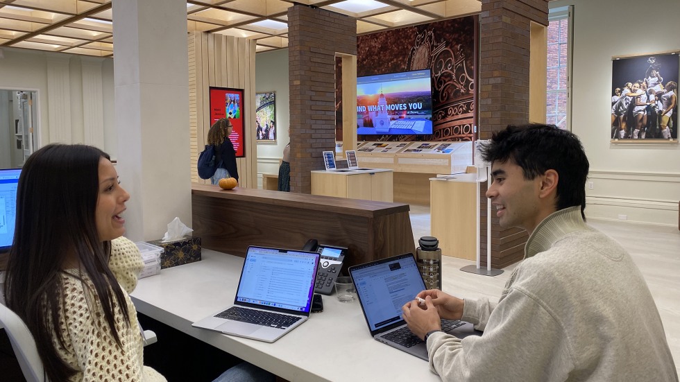 Charly Castillo and Nakhil Ahn talk at the welcome desk