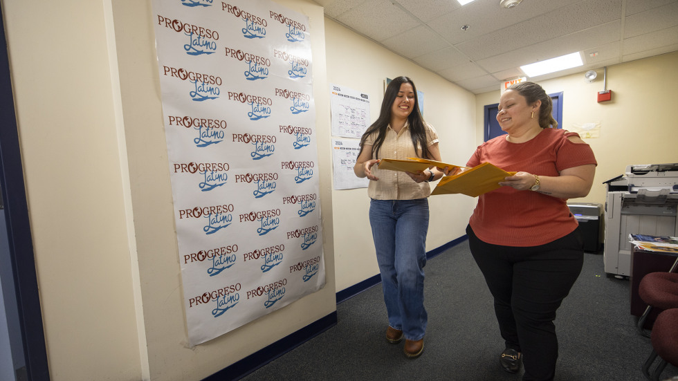 Brown undergraduate student walks down a hallway with her direct supervisor at local nonprofit Progresso Latino.