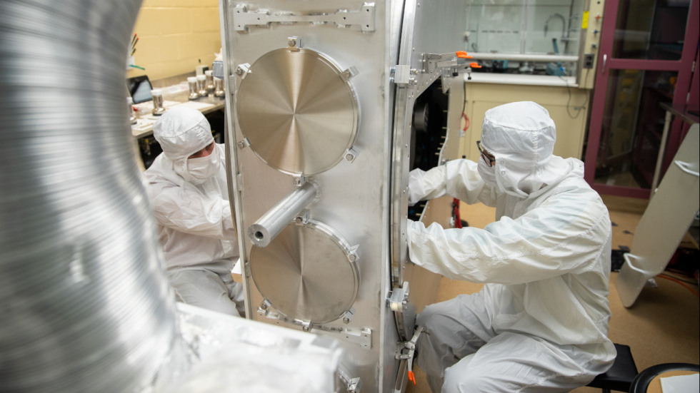a person in a white clean suit working on a large photomultiplier tube array