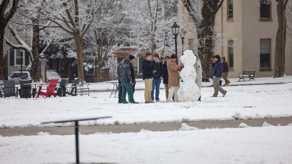 people gather around a snowman