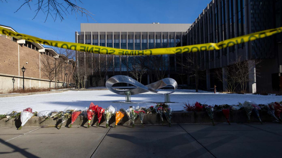 flowers on the ground outside of a building cordoned off with police tape