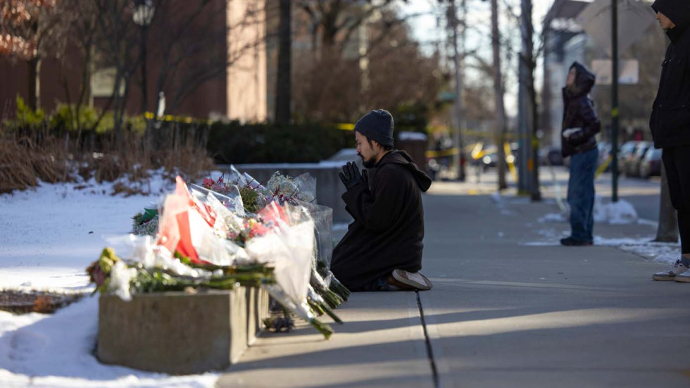 a person kneels to pray on a sidewalk