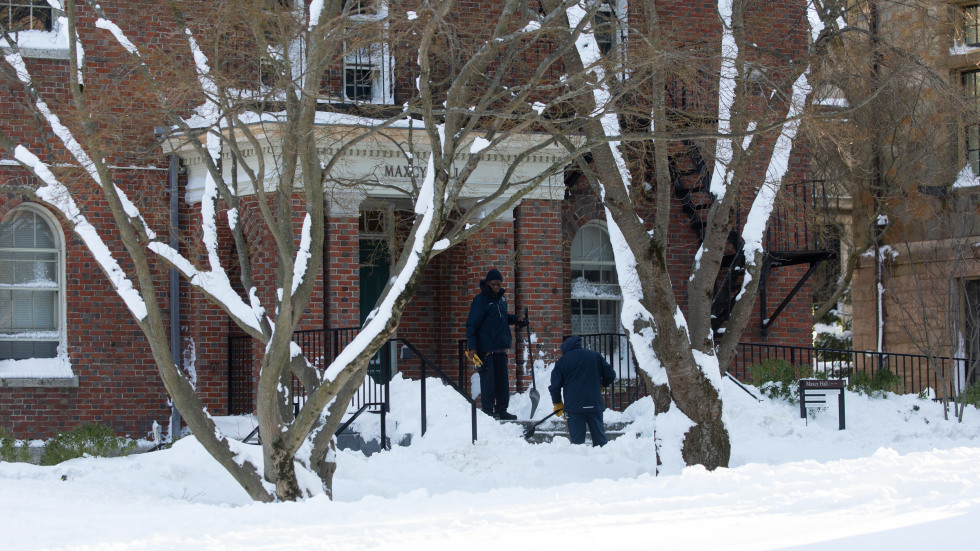 workers shovel steps at a campus building