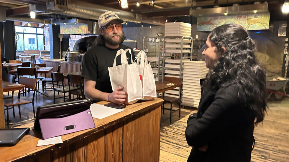 A manager at Flatbread Company smiles as a Brown student hands him a gift bag. 