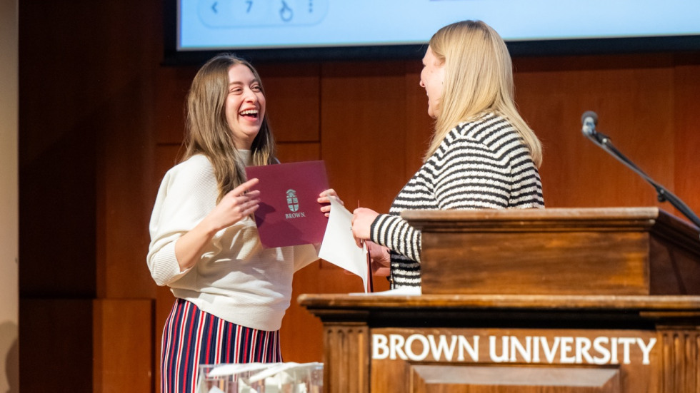 Two people exchange a laugh at a podium