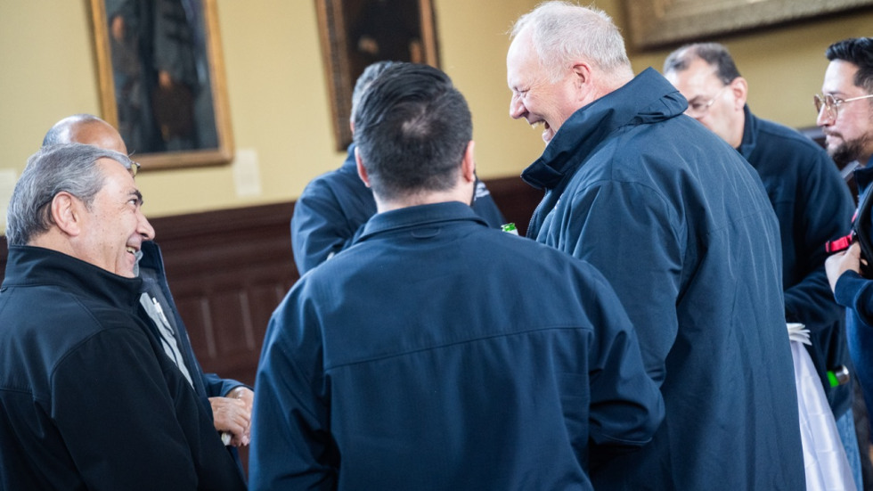 Brown staff members standing in a circle talking and smiling