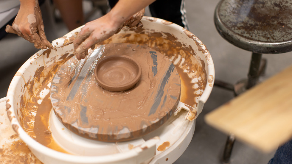 A small dish is ready to be removed from the pottery wheel base