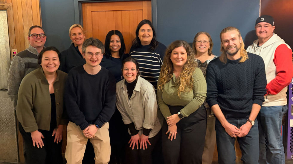 A group of Brown employees smile together as a group to take a photo at a city restaurant.