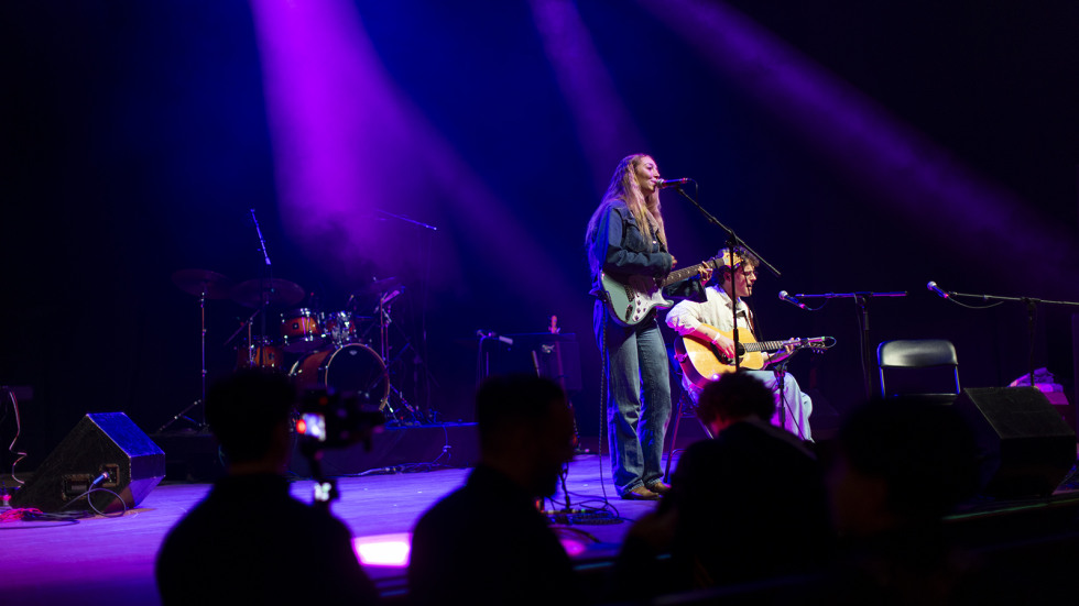 students play guitar and sing on a stage at the Strand Ballroom in Providence as part of a benefit concert. 