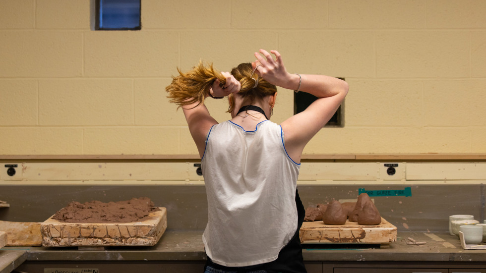 Sasha Watson puts her hair up before working with clay