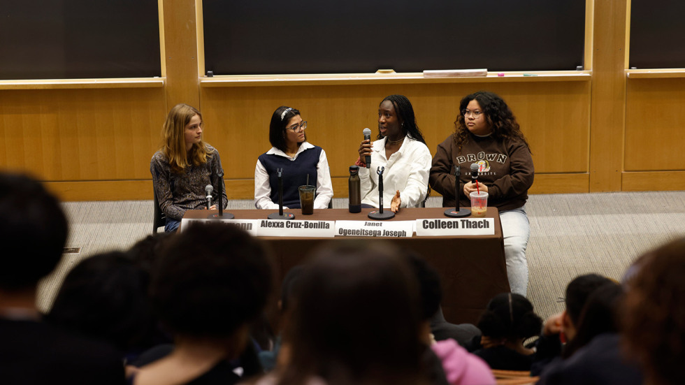 four people sitting at a table in front of an audience