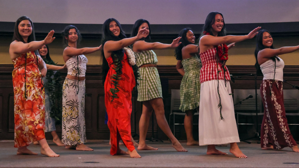 Students perform a hula on stage in Sayles Hall