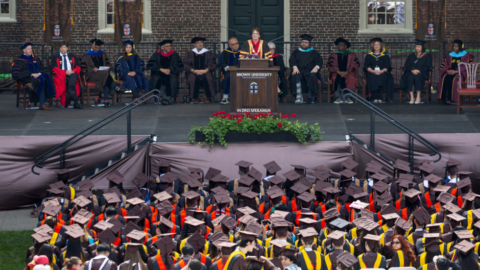 Wide shot of President Paxon speaking at podium in front of seated graduates