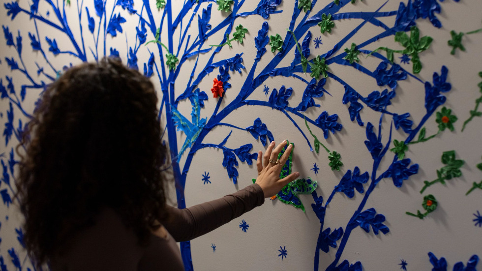 A student touches a tree in the mural