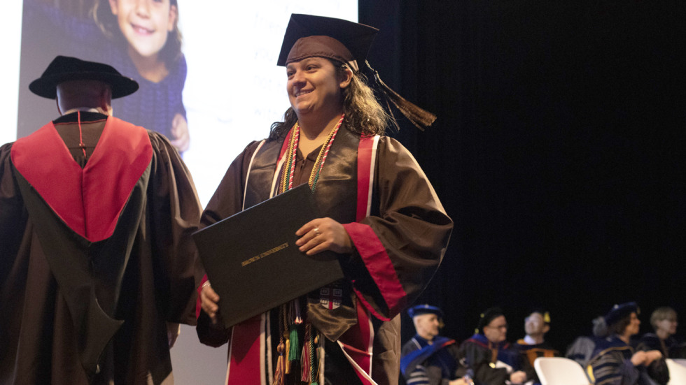 Brown student Lexi Pellegrino accepts diploma cover on stage